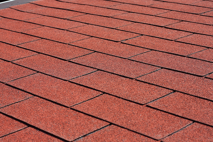 Professionally laid red asphalt shingle rectangular shape on a clean roof 